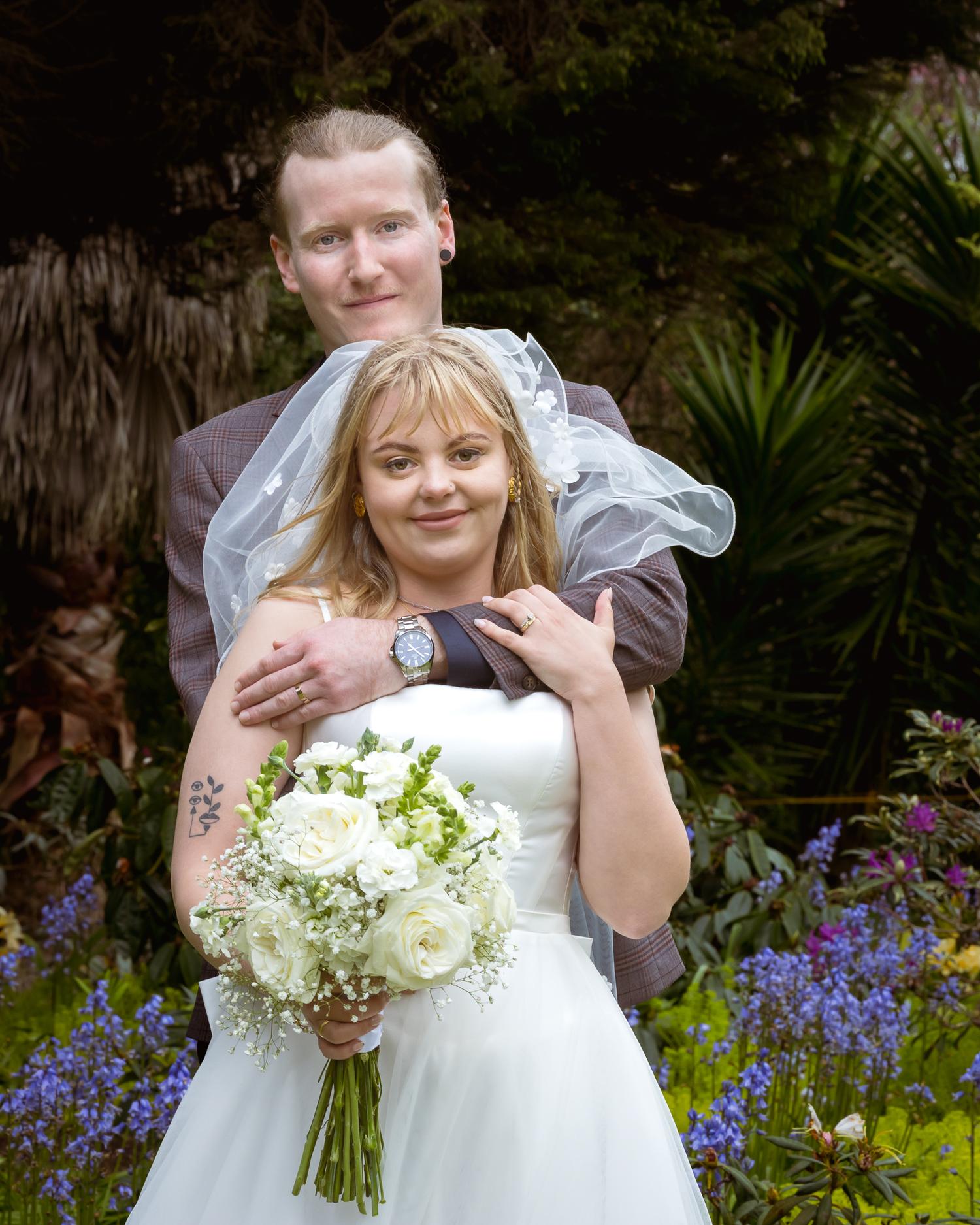 Connor hugs Shannon from behind among the bluebells