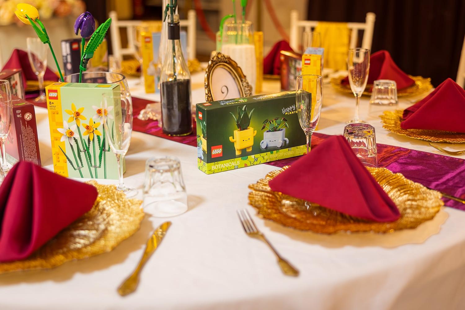A table set for a wedding with a box of Lego on it