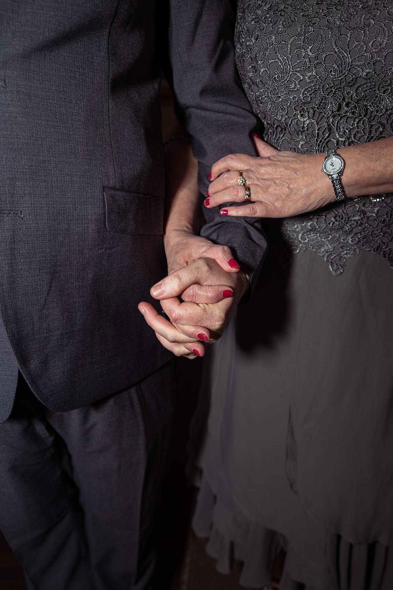 A man and woman are holding hands, possibly at a wedding