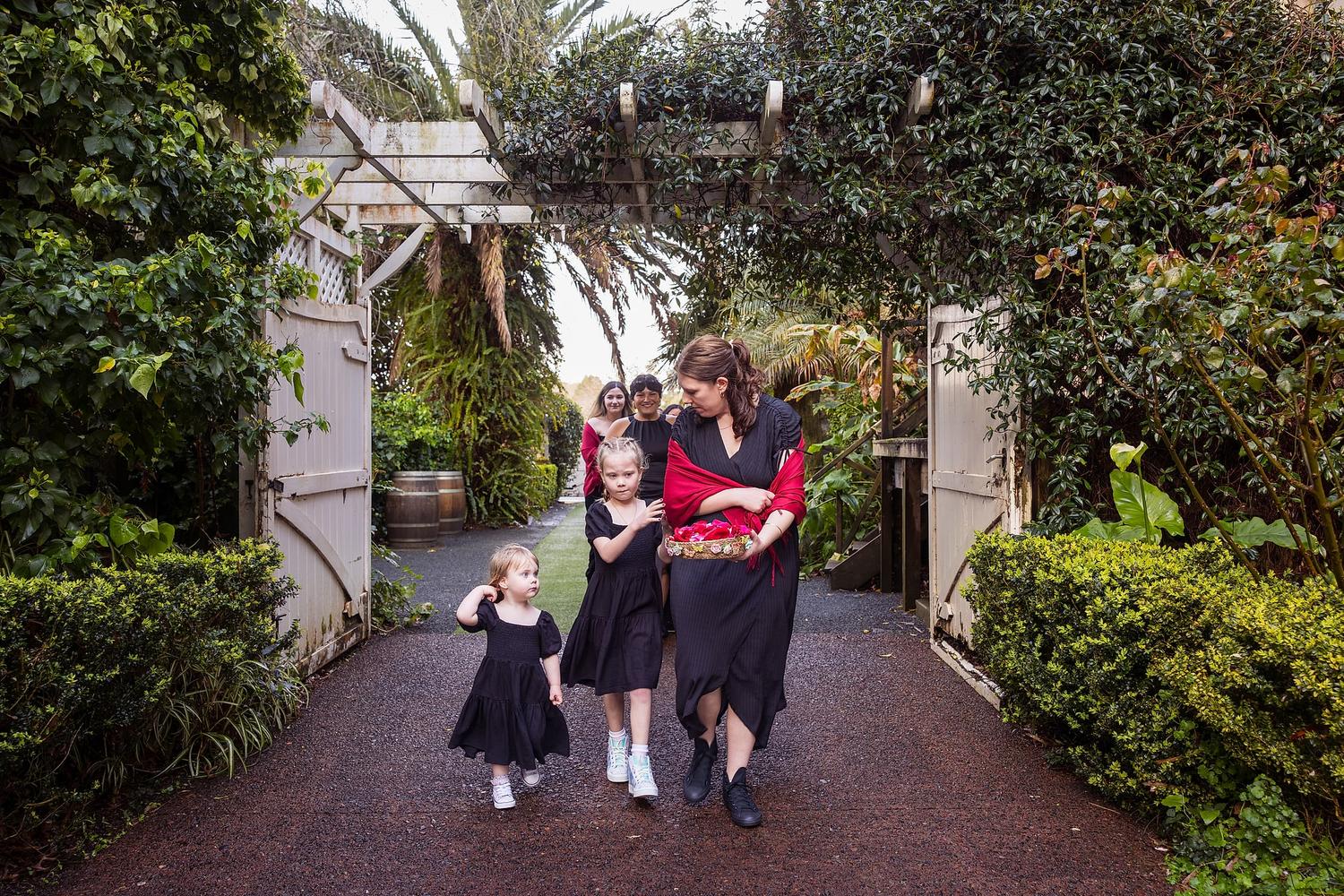 A woman and two children walk down a path, with the woman wearing a red scarf