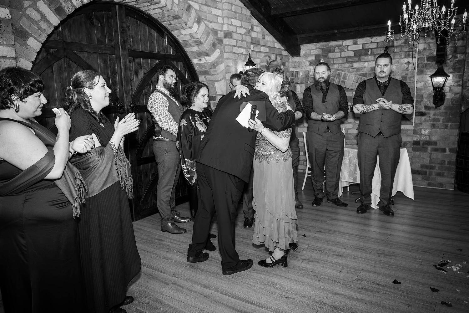 A group of people, including Josh and Paul, are hugging at a wedding
