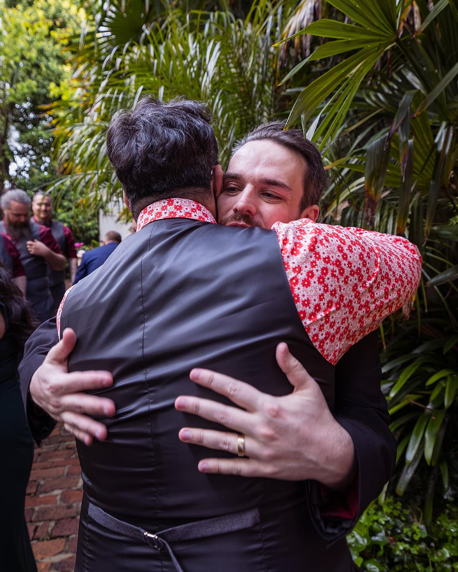 Two men, Josh and Paul, embrace at a wedding