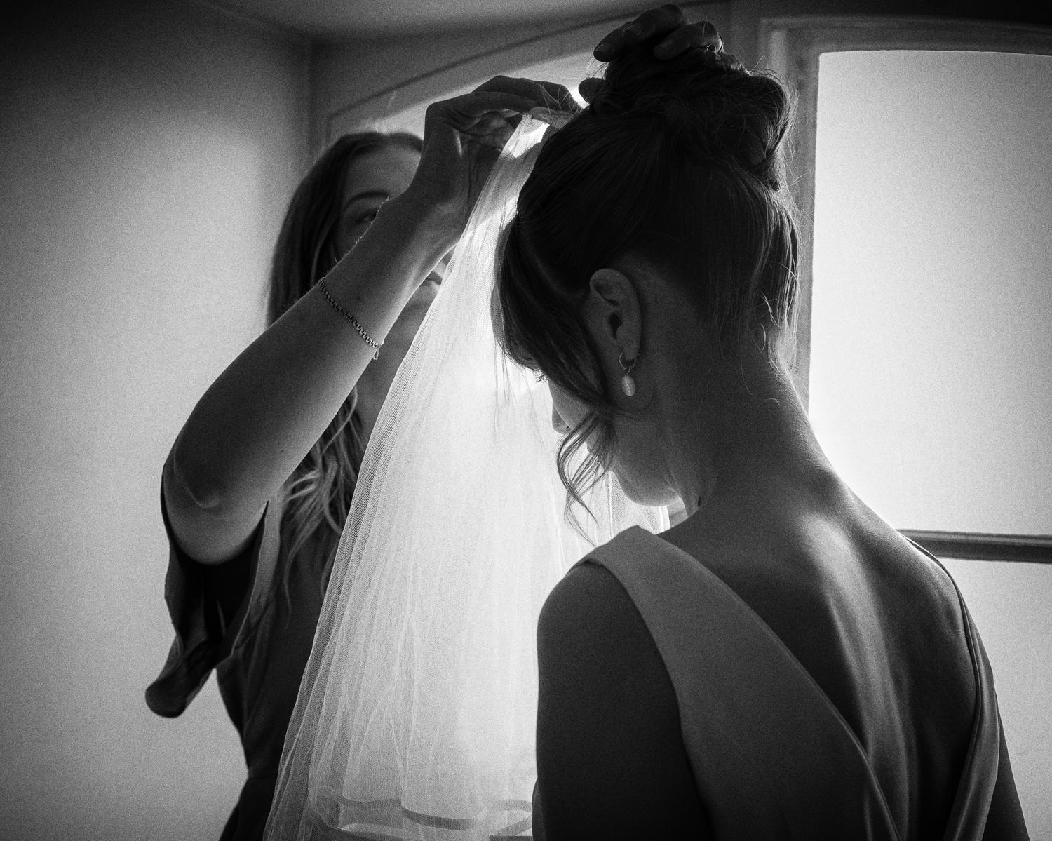 Black and white photo of Sofia’s veil being placed in her hair