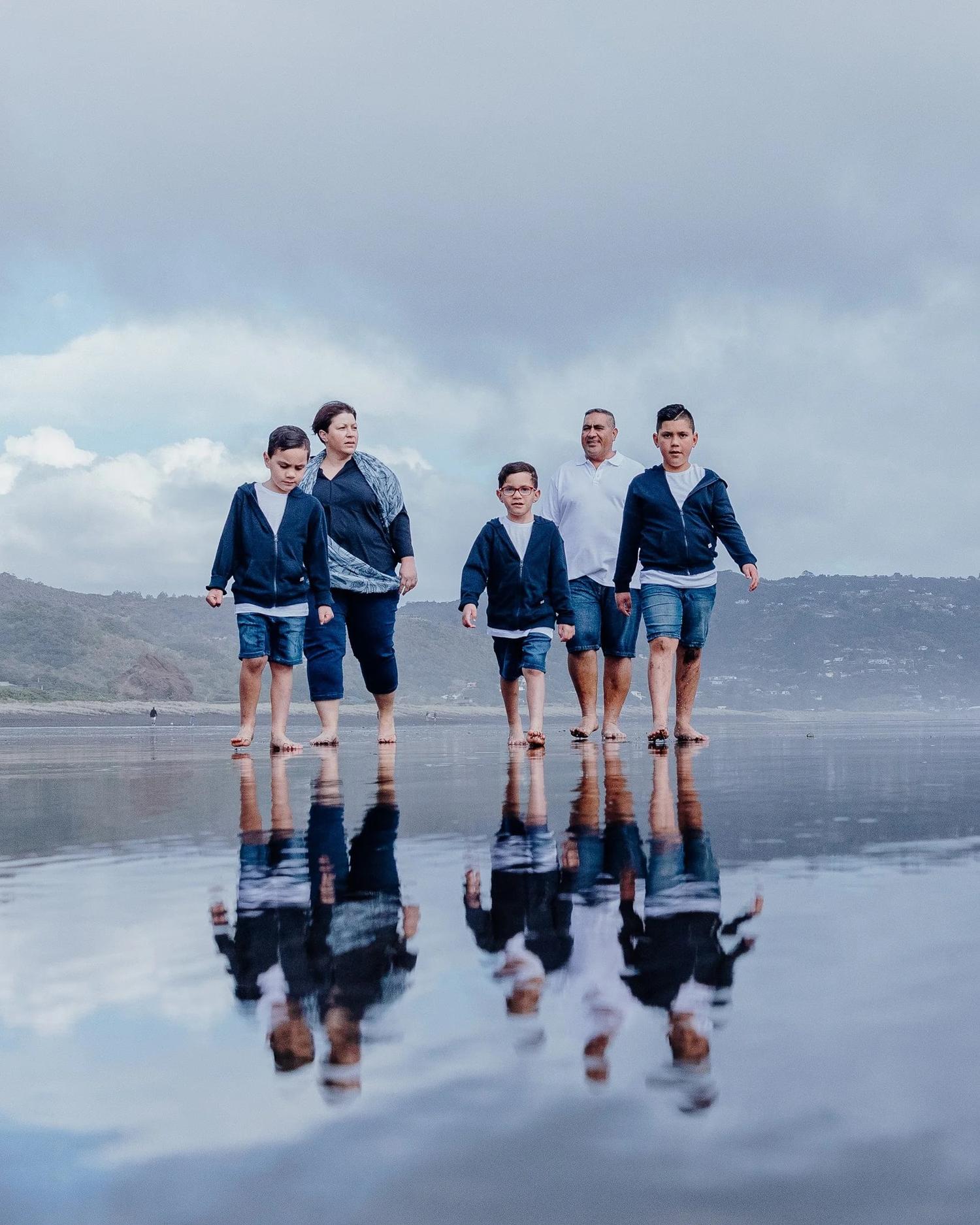 Tracey and her boys walk across the wet sand with reflections below