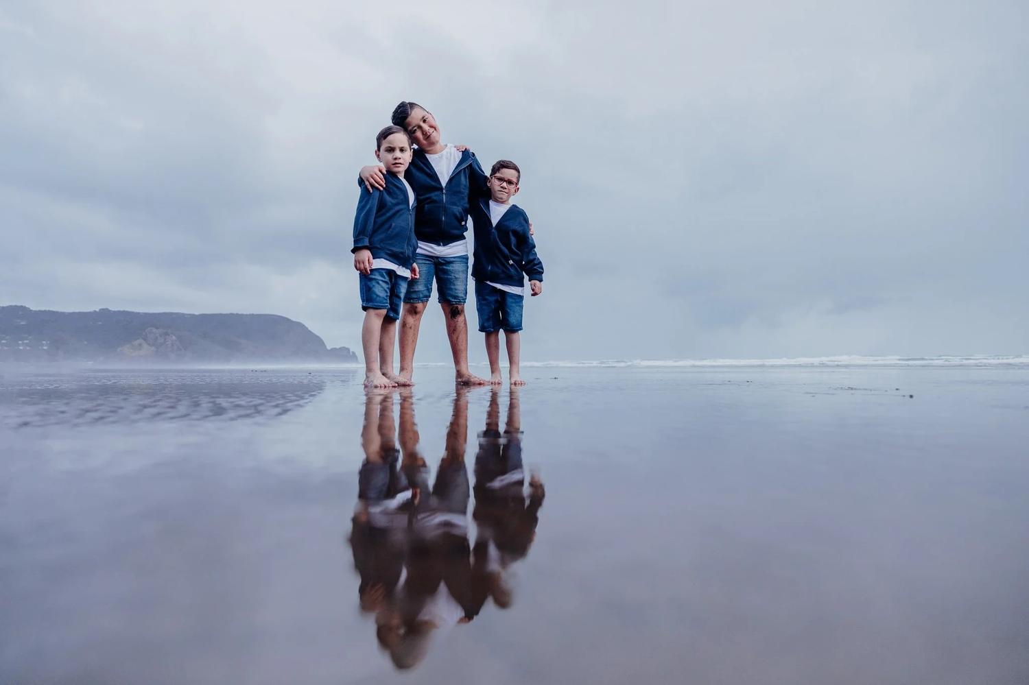 Tracey and her boys standing on a reflective beach