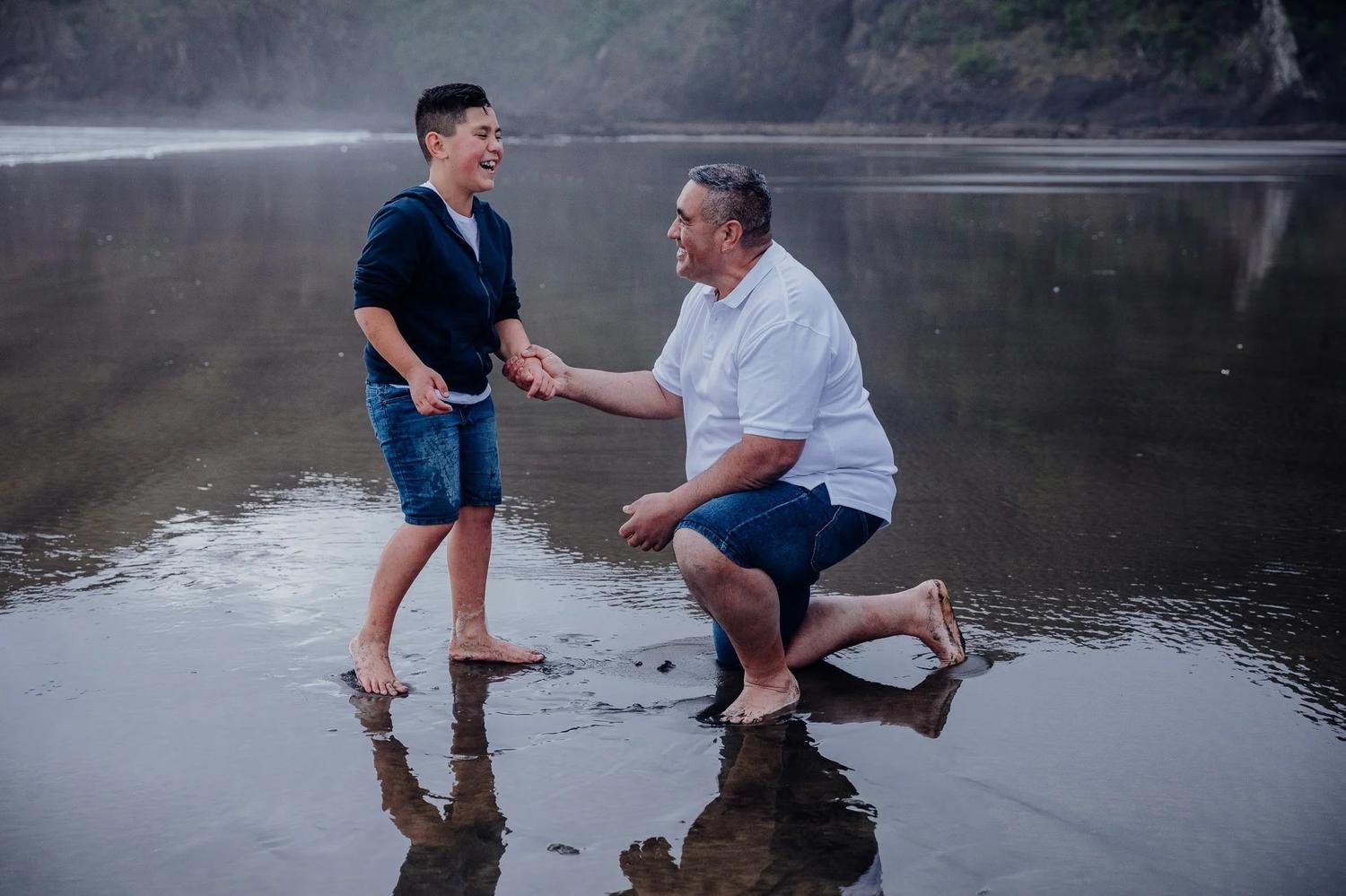 A boy and a man playing on the wet sand