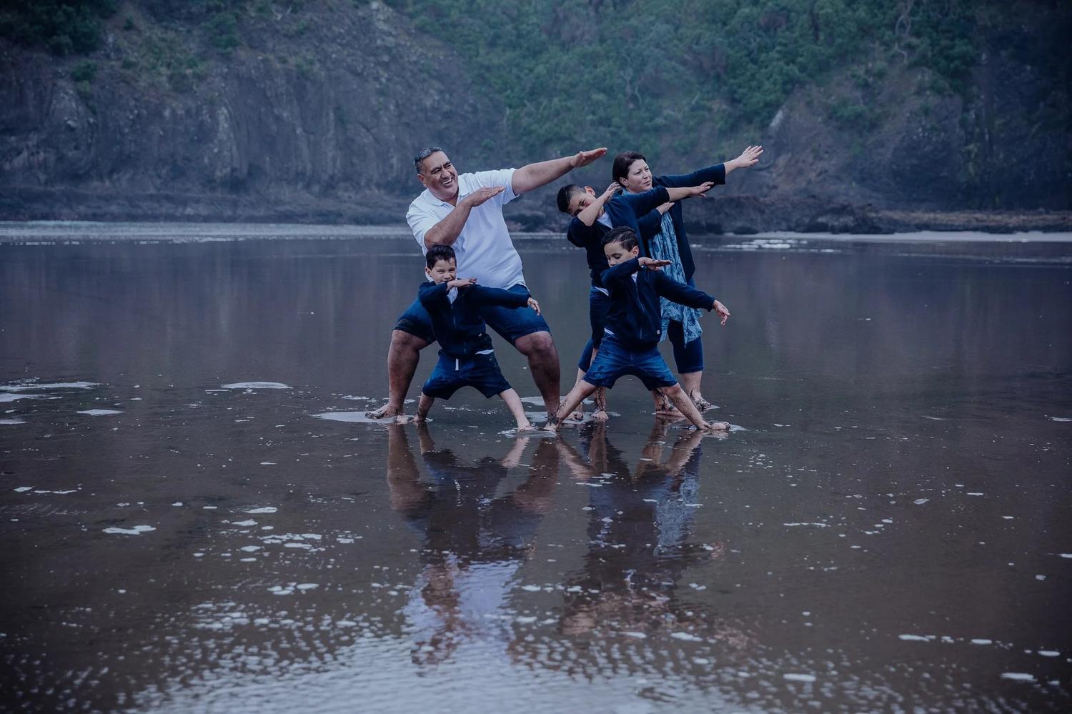 The family play-fights on the wet sand