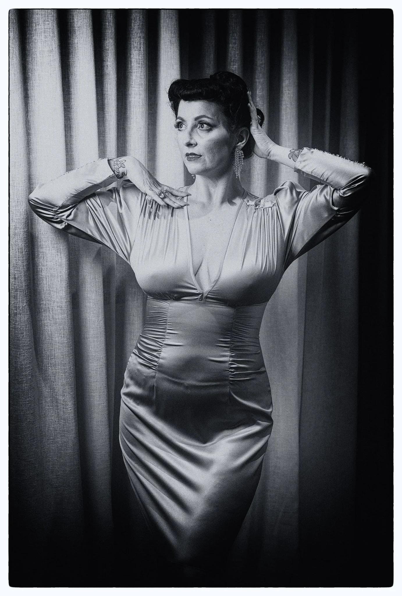Black and white photo of Viv in satin with hands behind her head