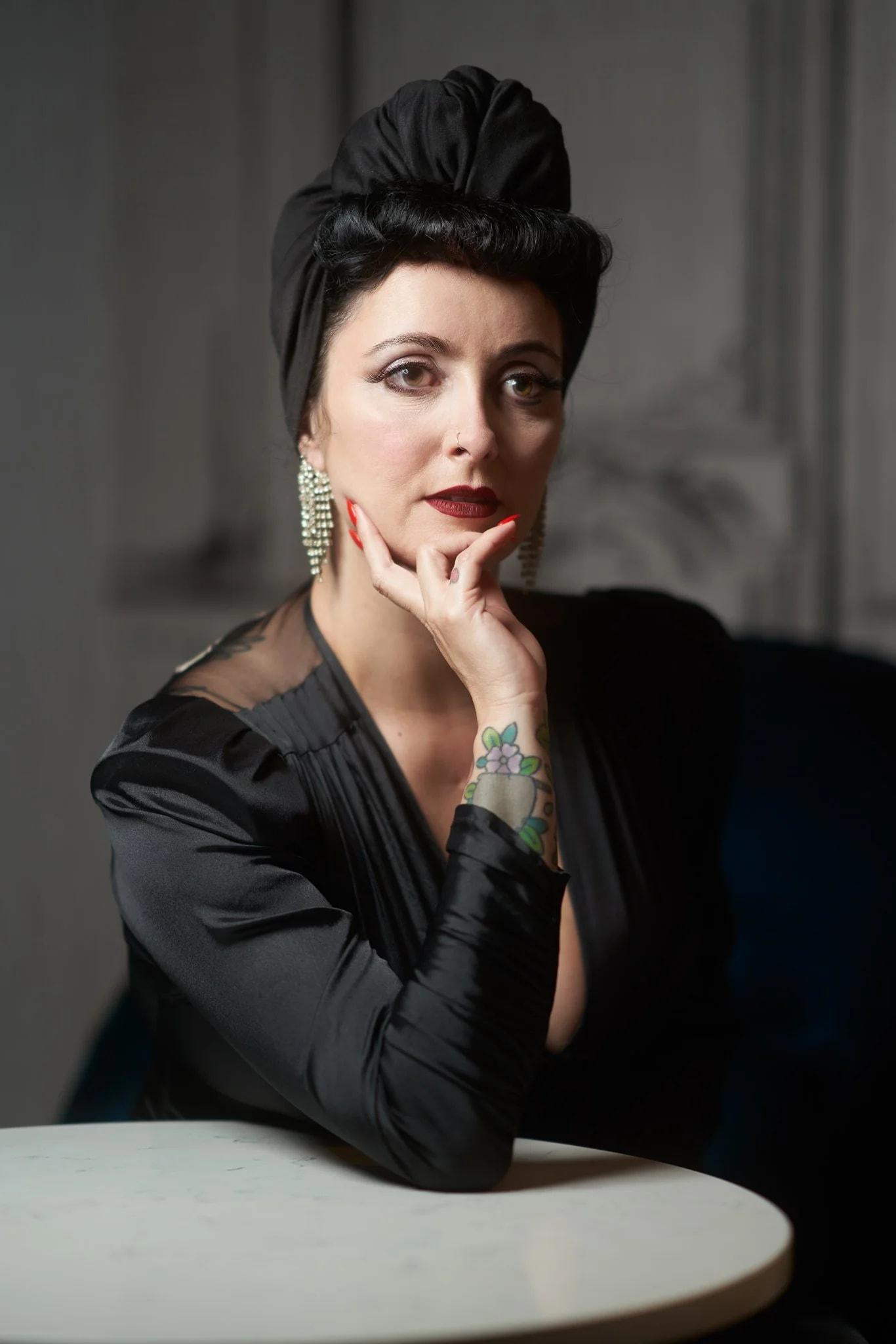 Viv in a black turban resting her chin on her hand