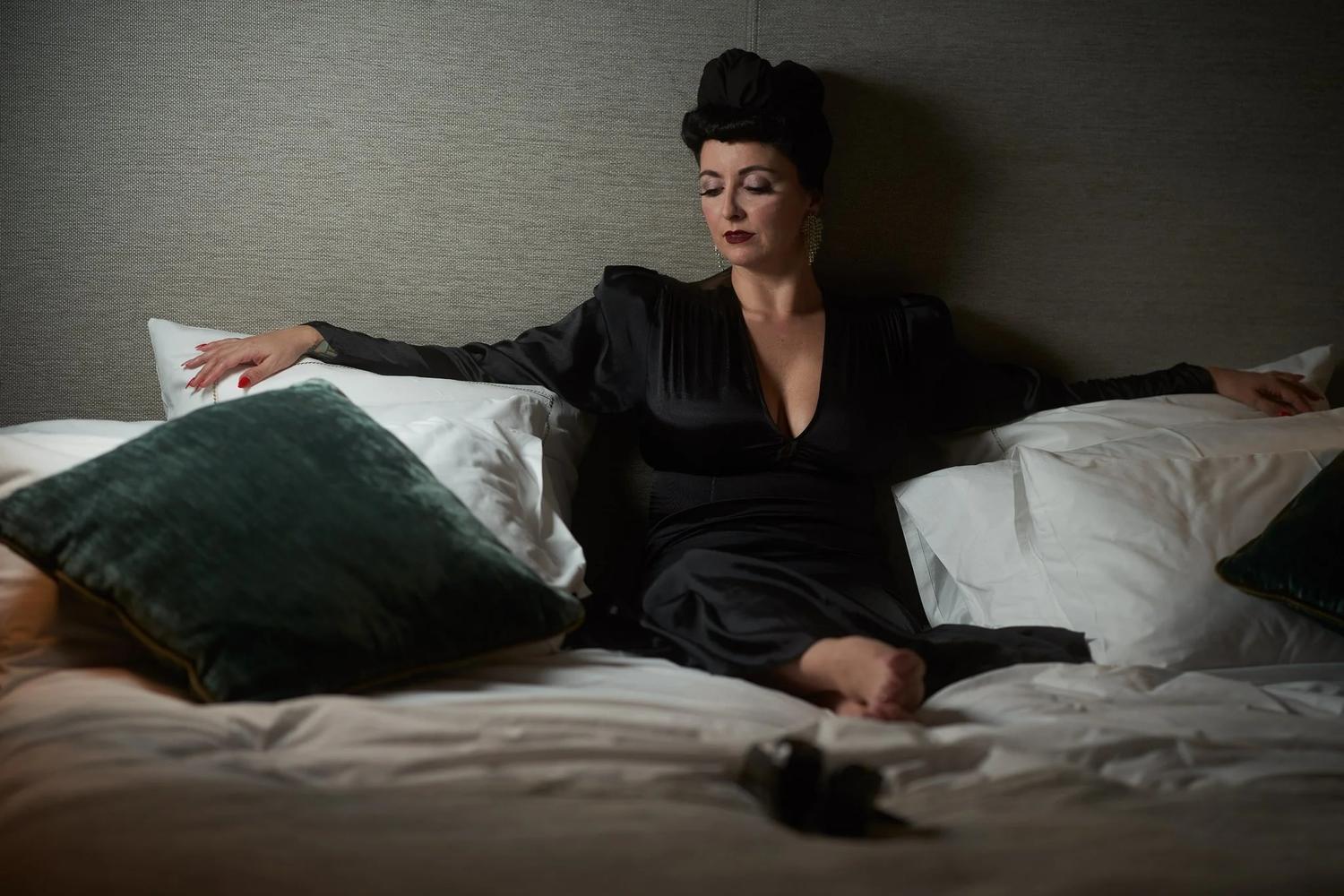 Viv reclines against cushions on a hotel bed