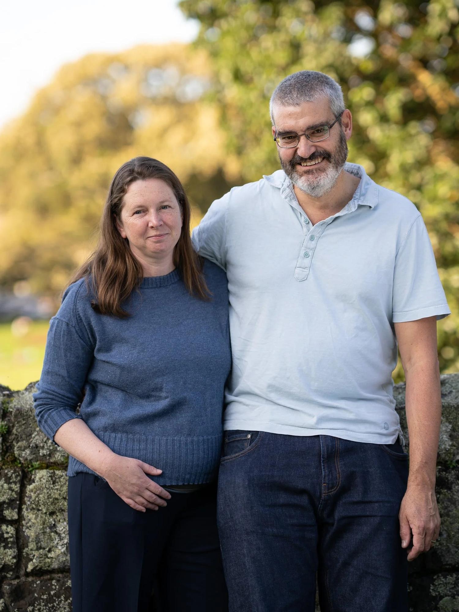 The parents smile at the camera in warm evening light
