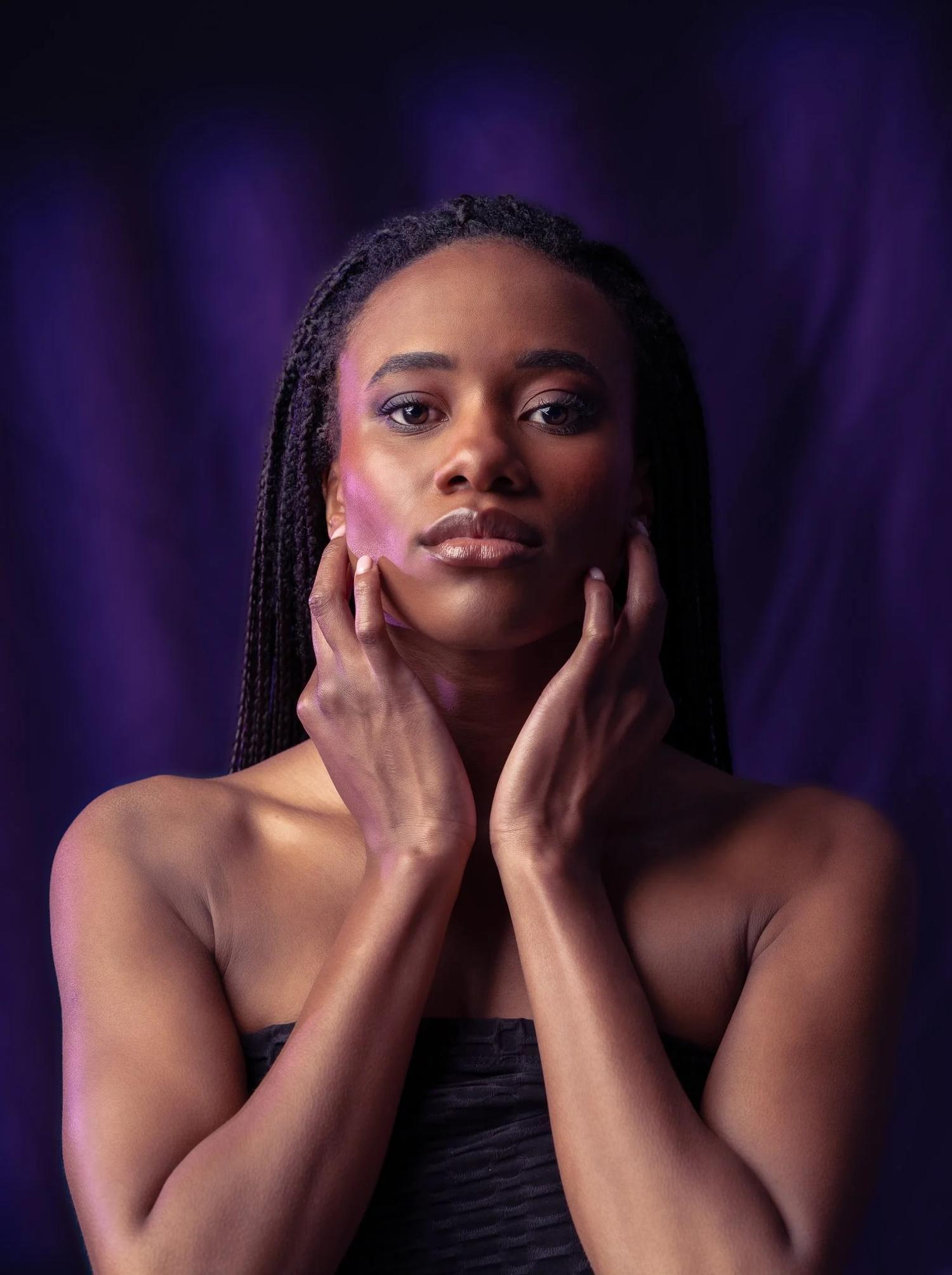 Ty holds her face in her hands in purple light