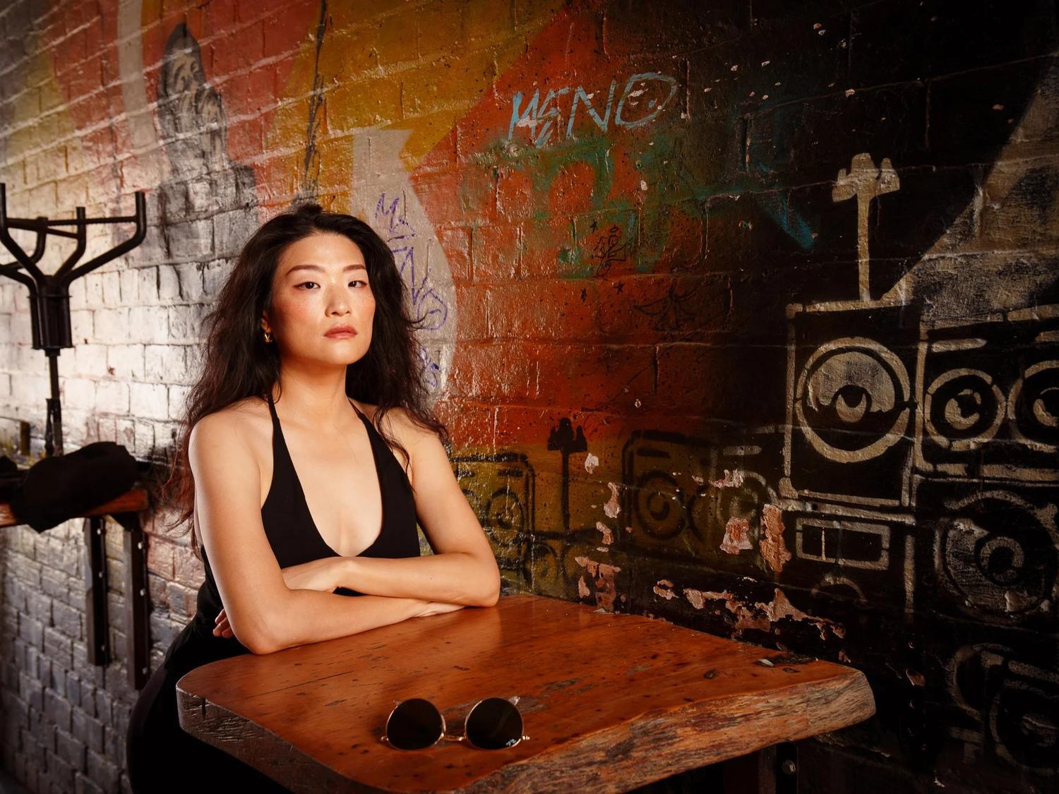Anna sits at a wooden table in a graffiti courtyard