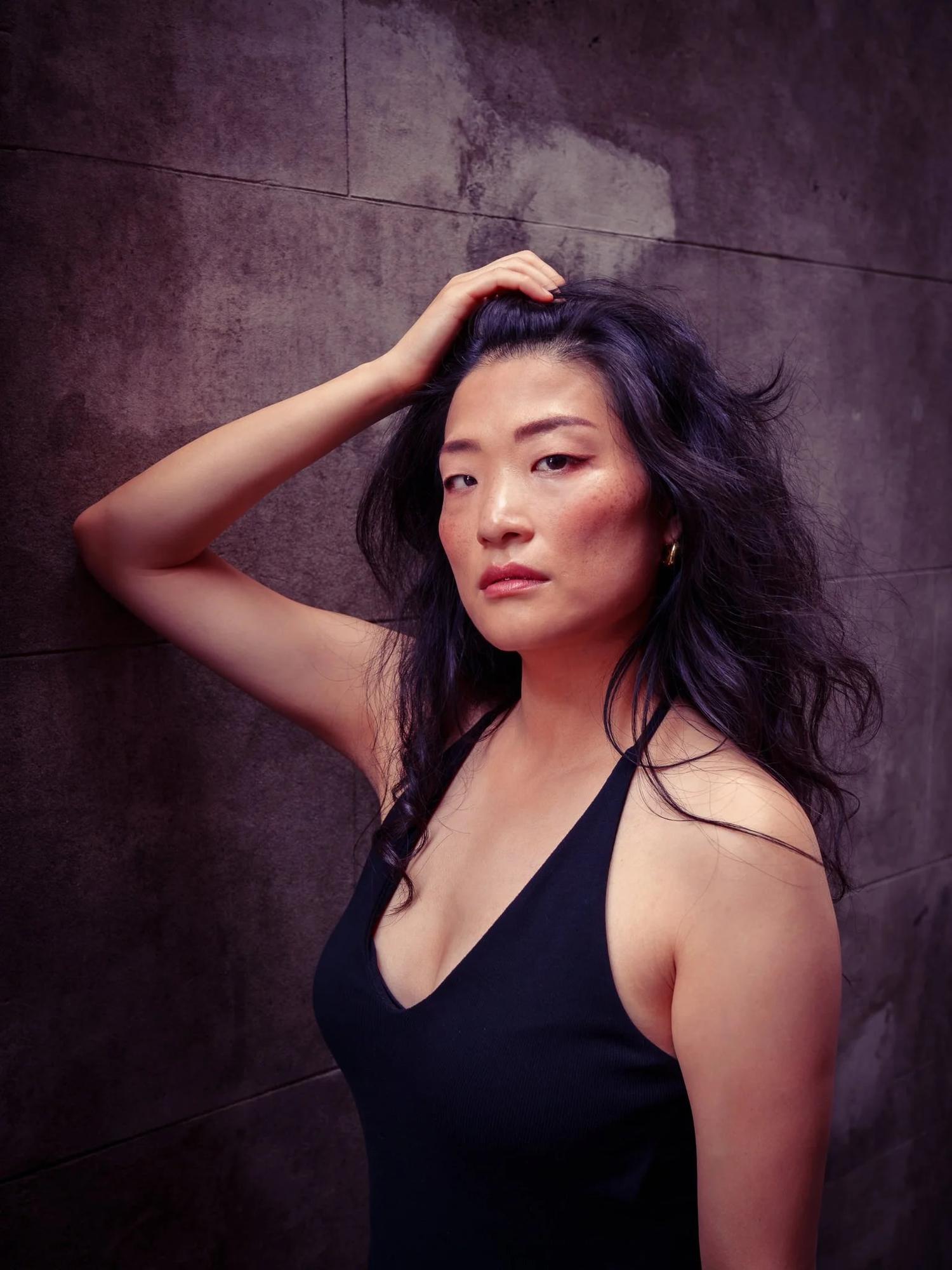 Anna with her hand in her hair against a dark wall