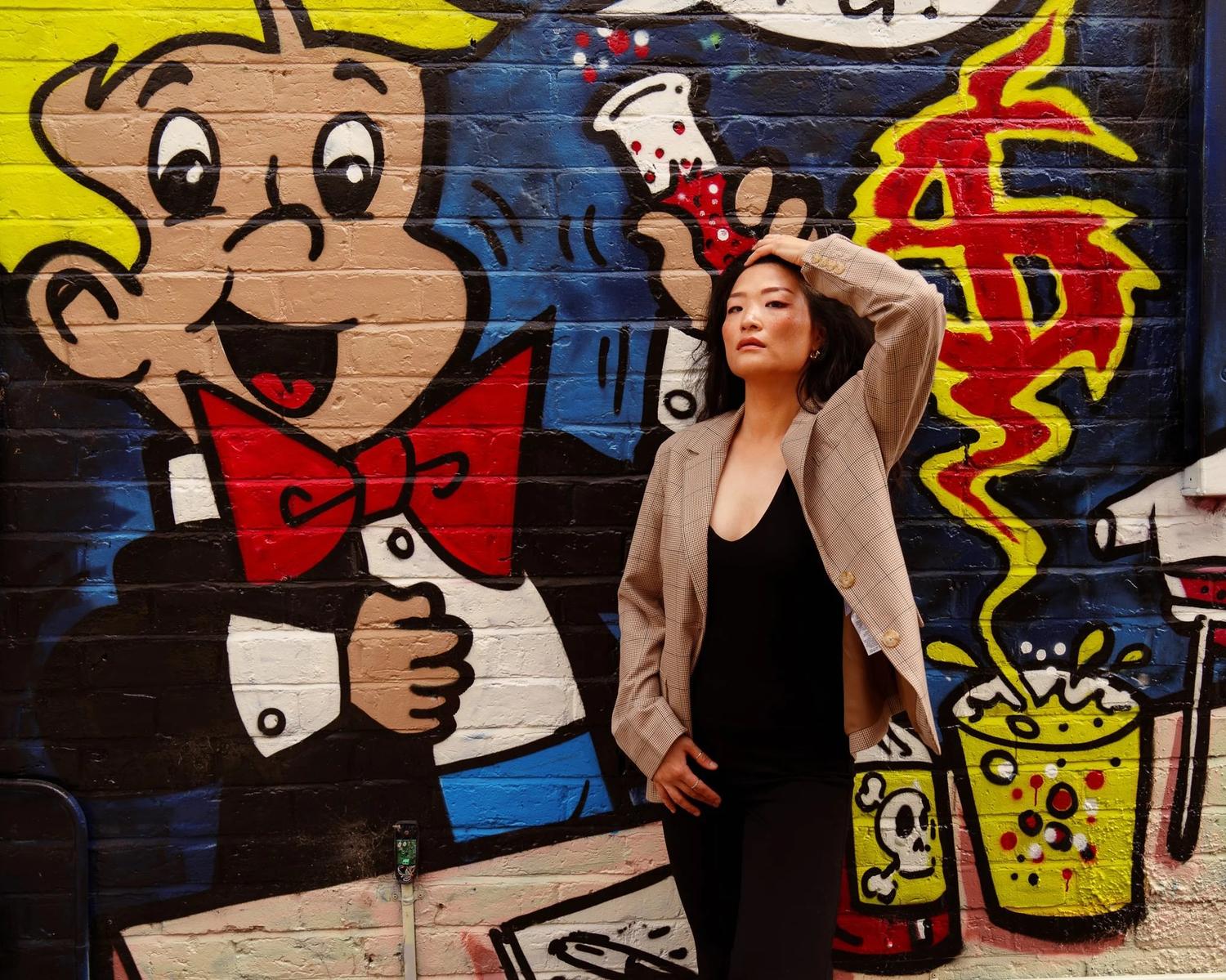 Anna in a blazer beside a colourful cartoon graffiti mural