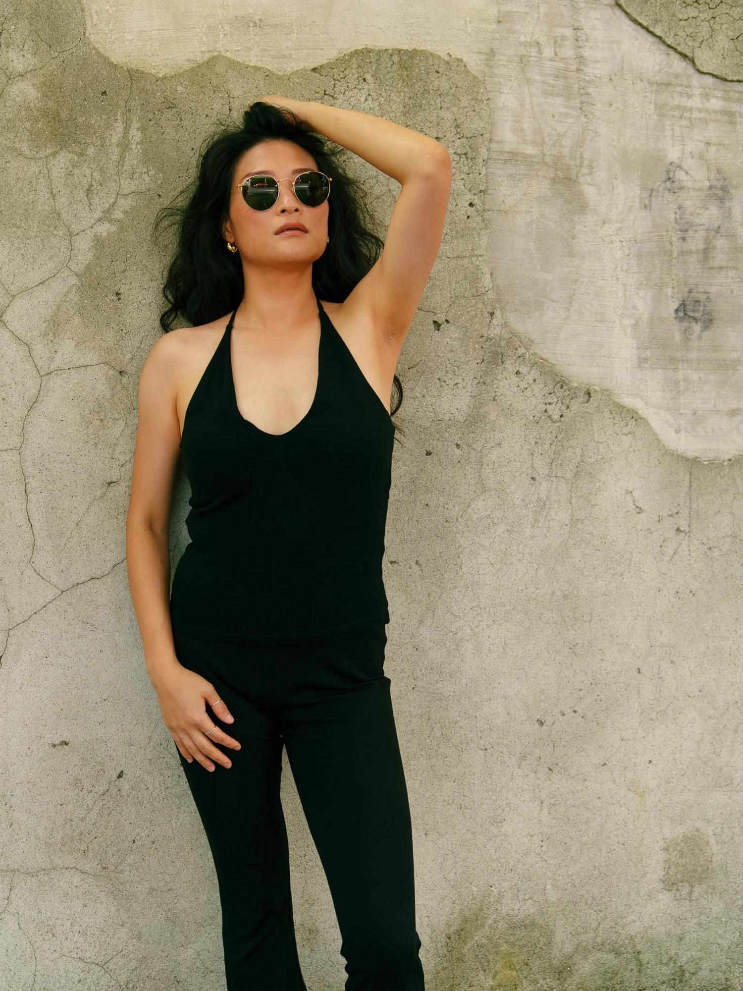 Anna in sunglasses against a weathered plaster wall