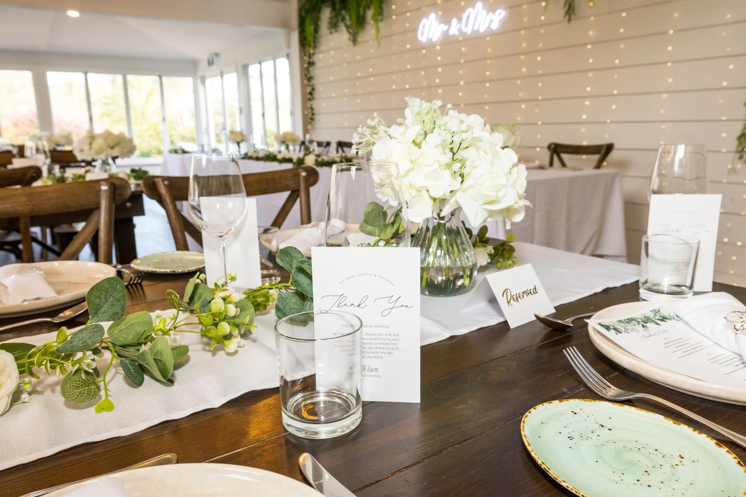 Reception table with a thank-you card, a place name card and white flowers