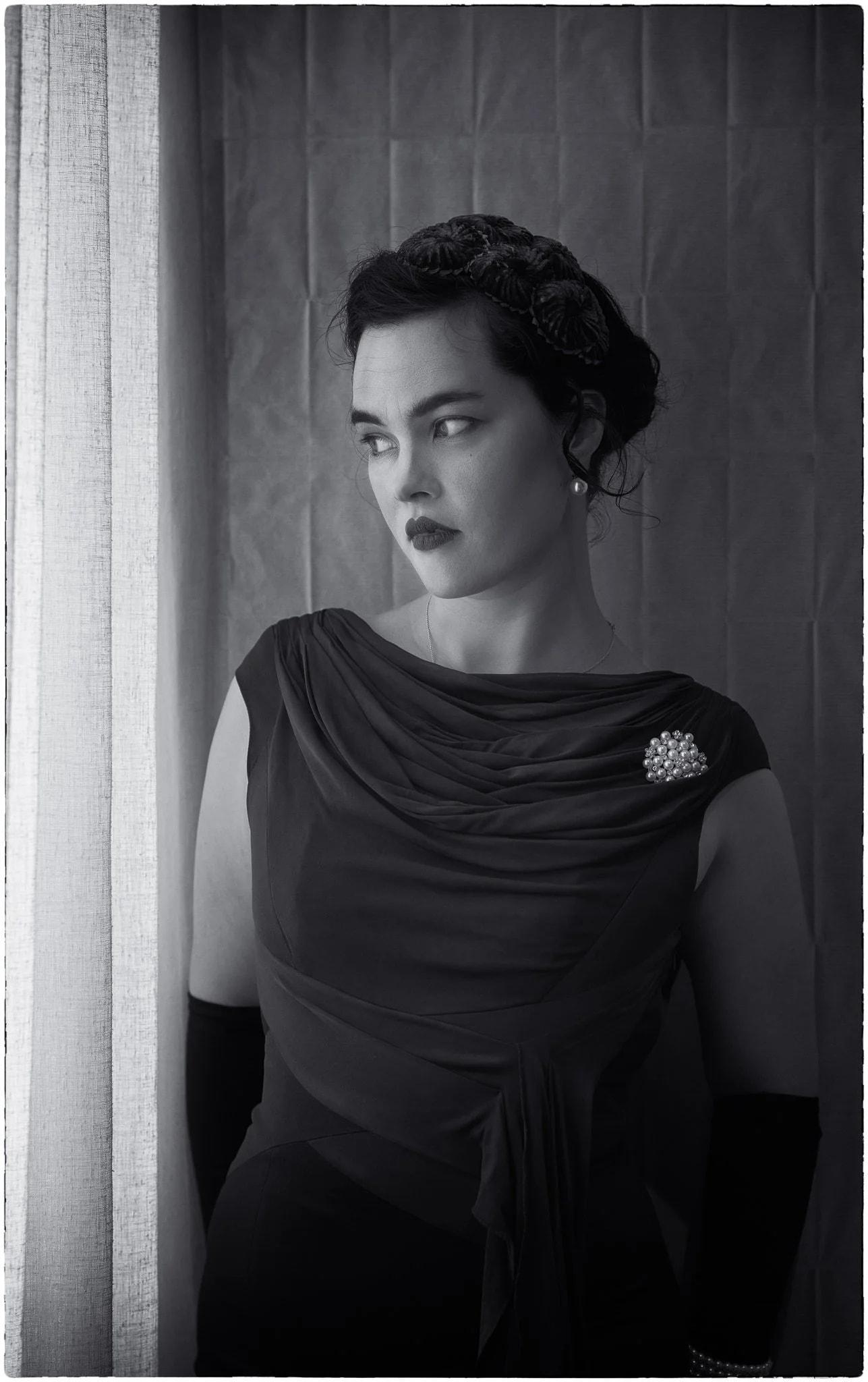 Black and white photo of Anita in long gloves by a window