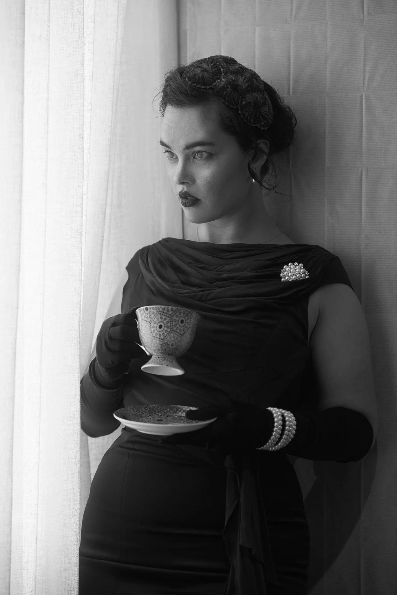 Black and white photo of Anita holding a teacup and saucer
