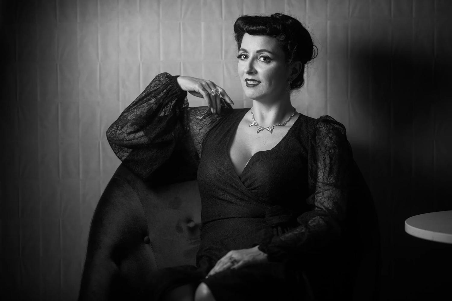 Black and white photo of Viv seated in a velvet chair