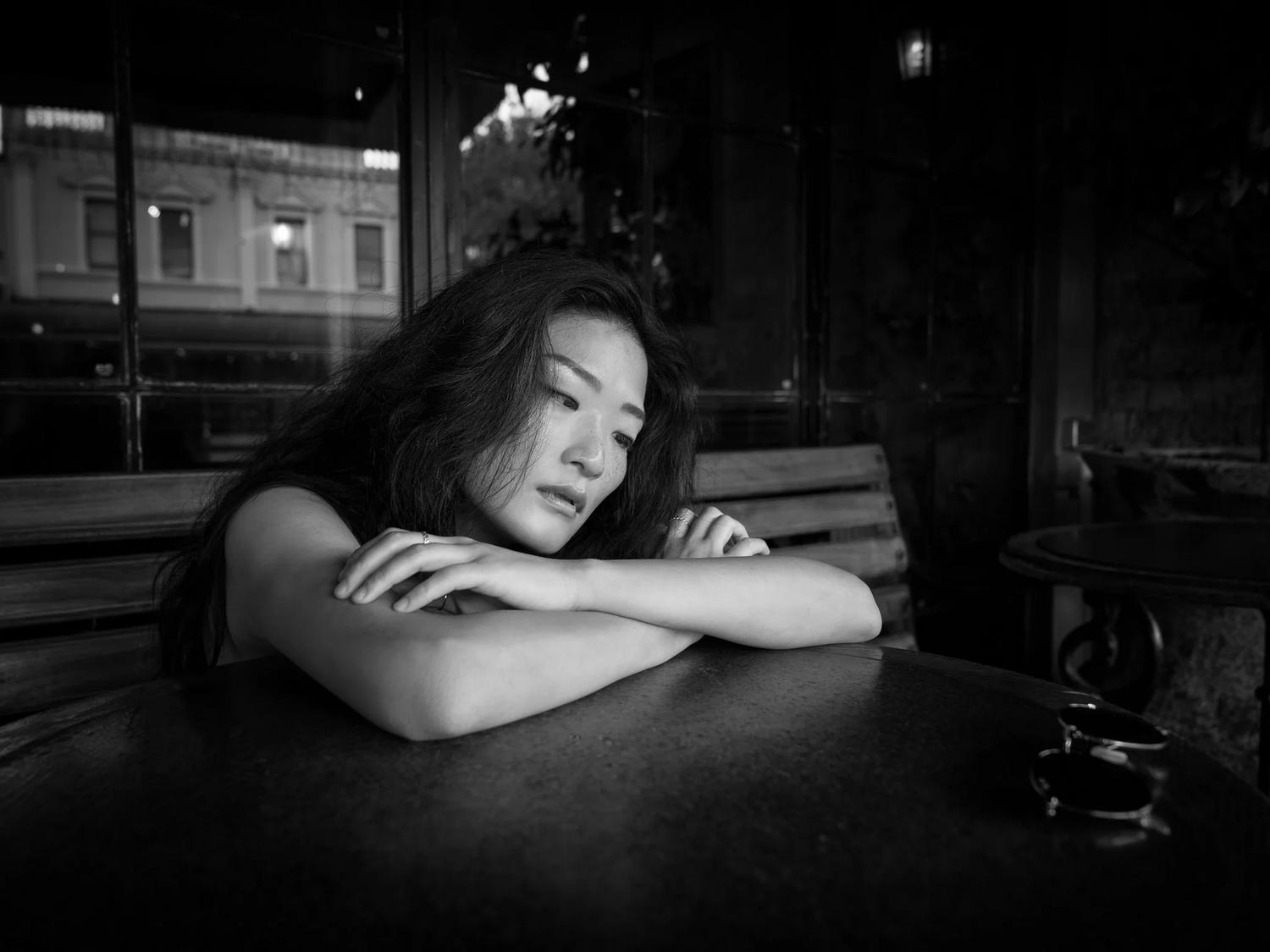 Black and white photo of Anna resting on her arms at an outdoor table