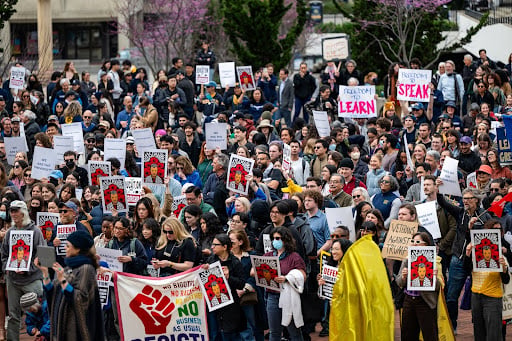 An image of a mass faculty rally, with people carrying placards with slogans.