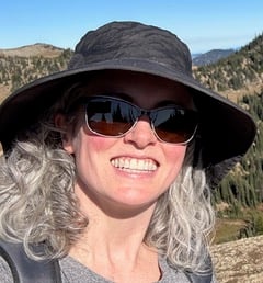 An image of a woman wearing a hat and sunglasses, facing the camera