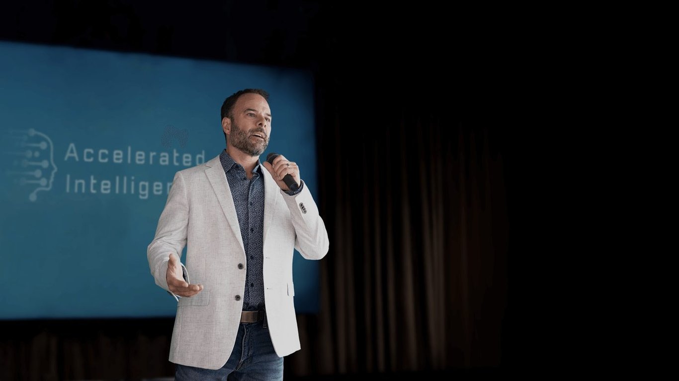 Brad Costanzo speaking with the Accelerated Intelligence slide behind him
