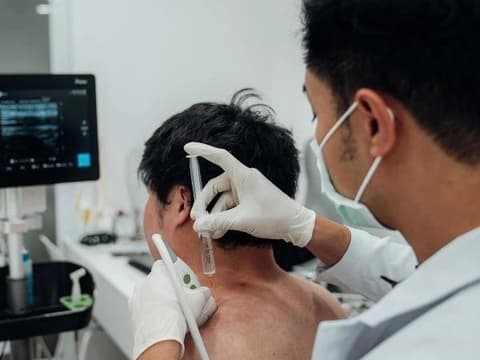 A physician using ultrasound guidance during an injection at the upper neck
