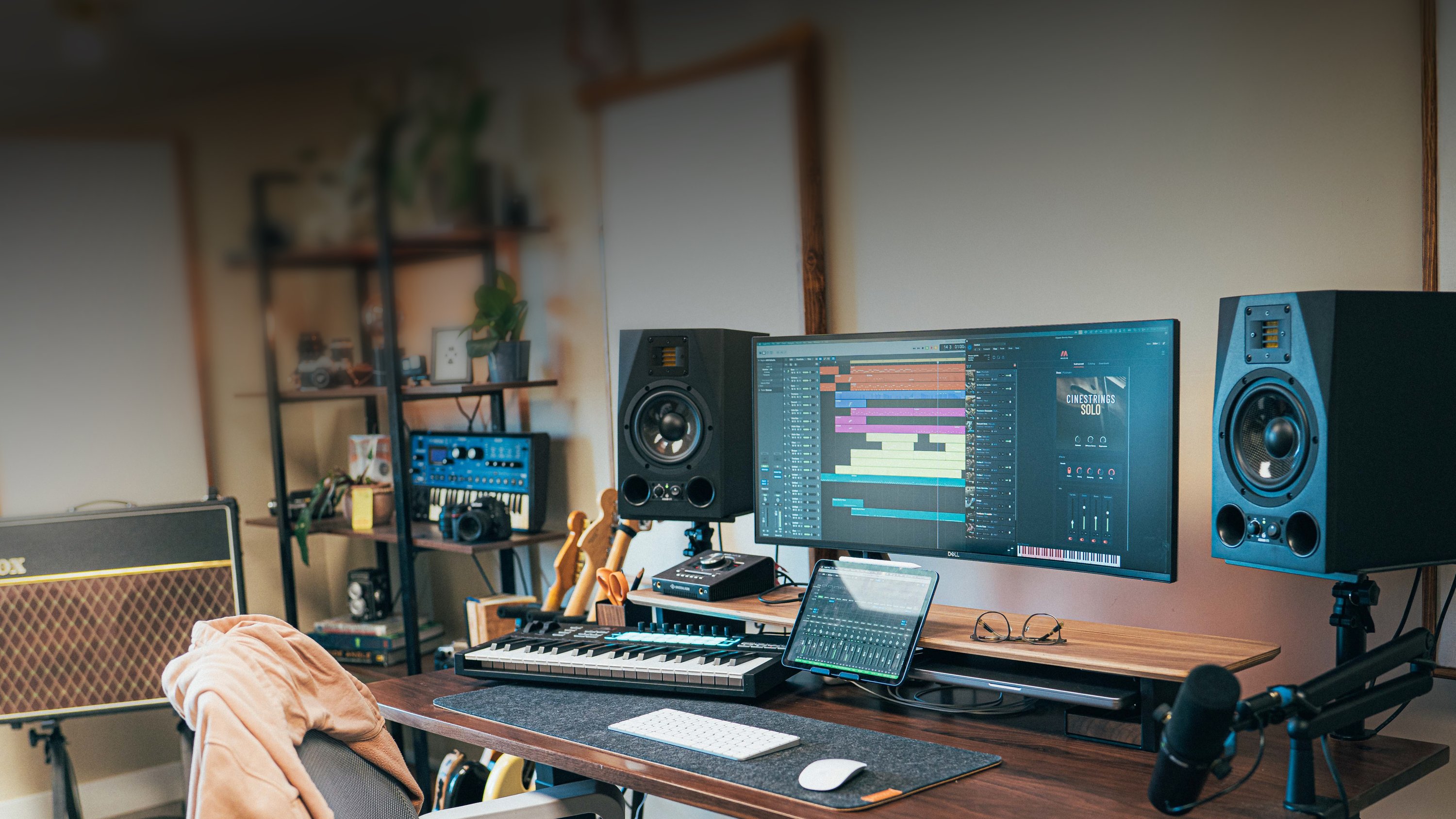 Music production desk with monitors, speakers, and instruments.