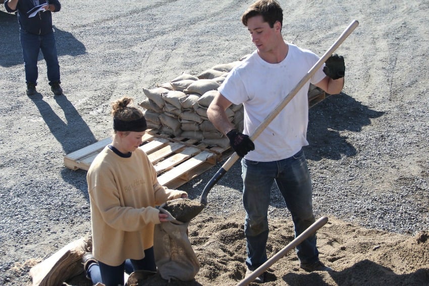 <who> Photo Credit: KelownaNow </who> City of Kelowna Staff on day six of filling sand bags and loading pallets. Each pallet holds 60 bags.