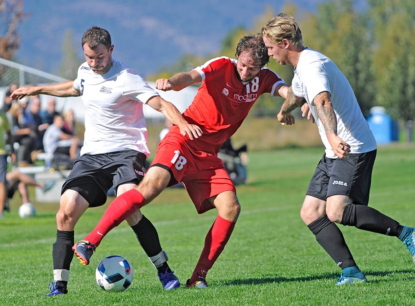 <who>Photo Credit: Lorne White/KelownaNow </who>Corey Wallis of Pikeys double-teamed by Alves Bros. FC's Étienne Myette-Cote, left, and Jack Orchard.