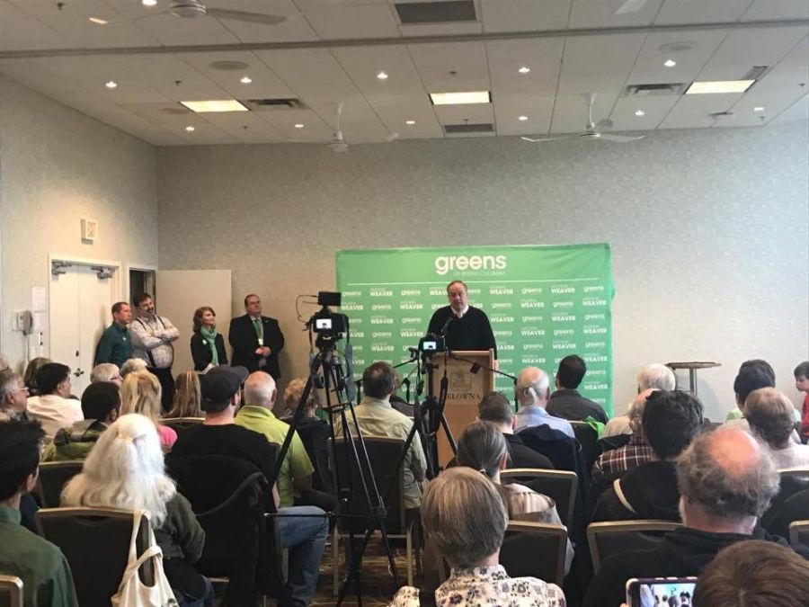 <who> KelownaNow </who> Andrew Weaver speaking to a crowd in the Best Western hotel 