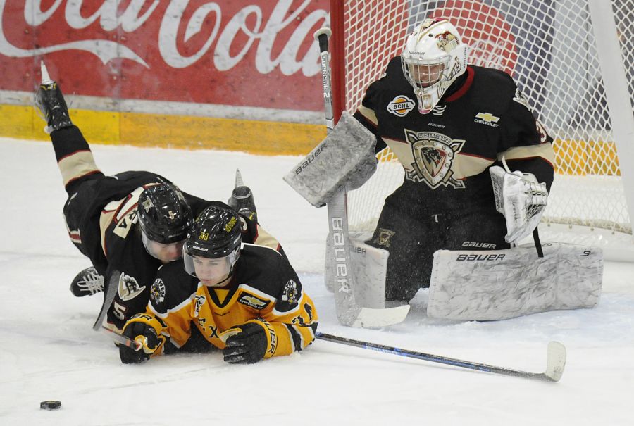 Spencer Hora, left, of the Warriors and Will Margel of the Express battle for the puck while flat on the ice in front of West Kelowna goaltender Brock Baier.