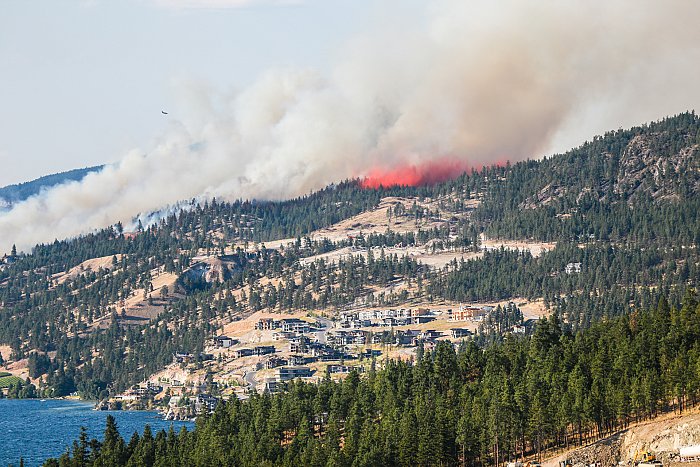 <who> Photo Credit: KelownaNow. </who> A water bomber hits the raging wildfire in Okanagan Centre in July, 2017. 