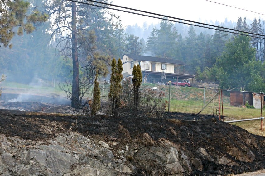 <who> Photo Credit: KelownaNow. </who> One of the many houses bordered by fire Sunday night. 