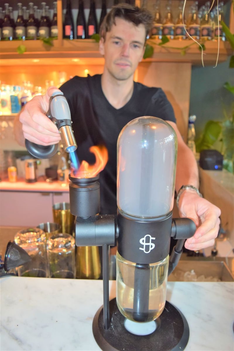 </who>Bartender Max Munsie uses a bong to create the smoke used in the Tom Ford cocktail.