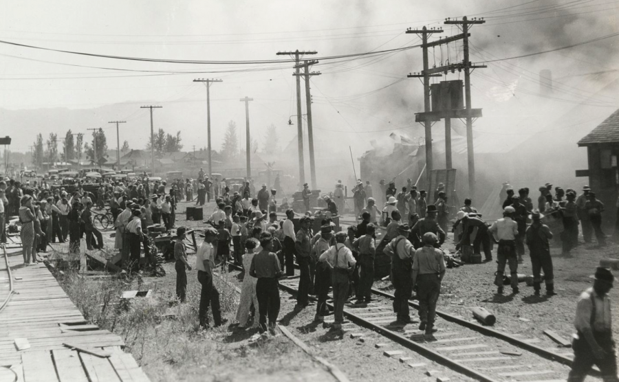 <who> Photo credit: Okanagan Special Collections OSC ARC 02 001 003a 043a </who> A large crowd gathers to watch firefighting efforts at the stores or machine shop, 1937.