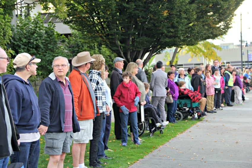 <who> Photo Credit: KelownaNow.com </who> Community members participating in the human chain.