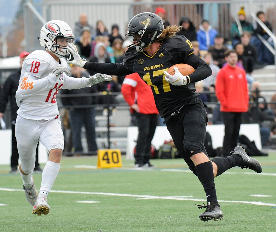 <who>Photo Credit: Lorne White/KelownaNow </who>Nolan Ulm of the KSS Owls straight-arms Jake Oseen of the Carson Graham Eagles enroute to a touchdown in the first quarter of Saturday's 62-21 win at CNC Stadium.