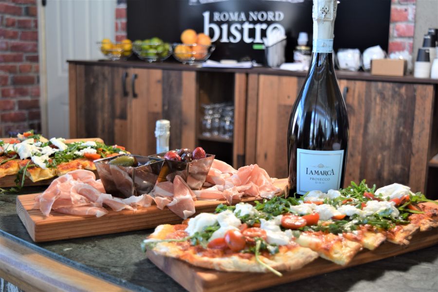 </who>Pinza-style pizza, foreground, with LaMarca Prosecco and prosciutto and olives in the background.