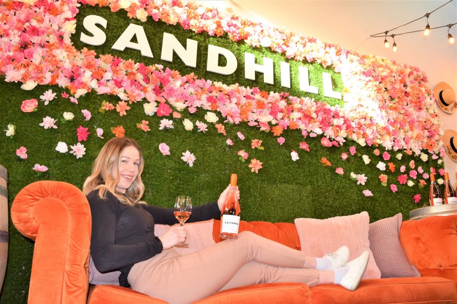 </who>Estate manager Brittany Price lounges on the couch at Sandhill Winery's Instagram-worthy, flowers-and-neon-lights Rose Wall.