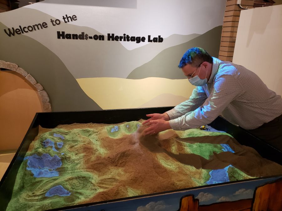 <who> Photo Credit: NowMedia </who> Penticton Museum Curator Dennis Oomen plays in the augmented reality sand box.