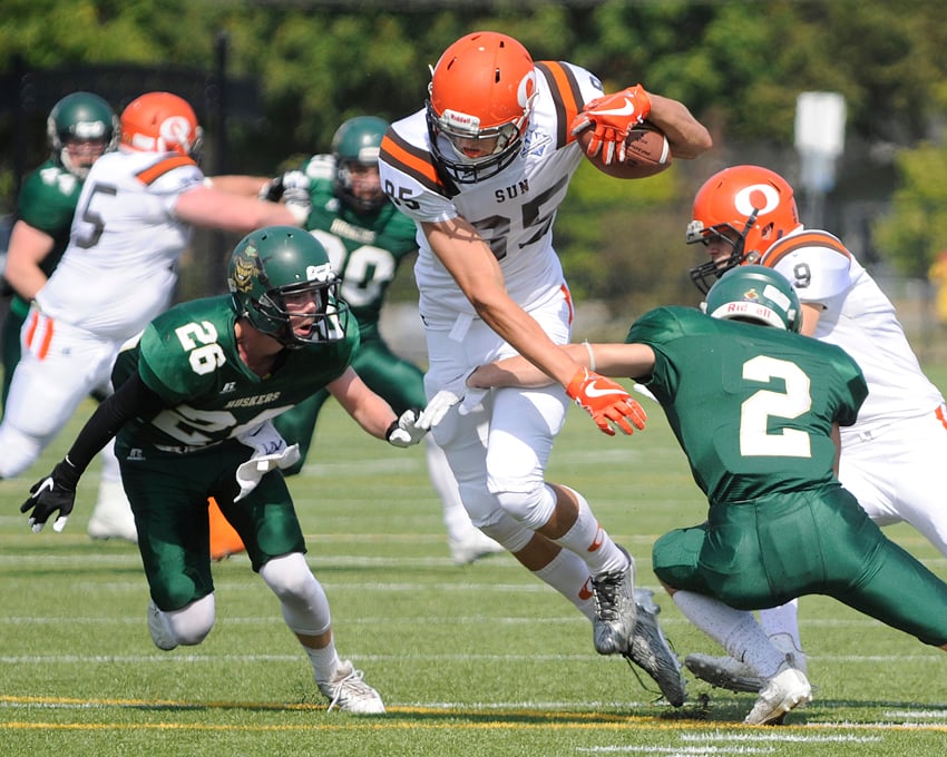 <who>Photo Credit: Lorne White/KelownaNow </who>Jesse Falconer eludes a pair of Valley Huskers on the way to a touchdown early in the Okanagan Sun's 42-3 win in Chilliwack.