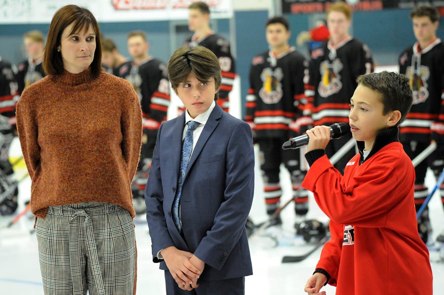 <who>Photo Credit: Lorne White/KelownaNow </who>Twelve-year-old Scott Berg sings a stirring rendition of Hallelujah prior to Friday's game in honour of Grant Sheridan. Looking on are Sheridan's wife Cherie and son Tanner.