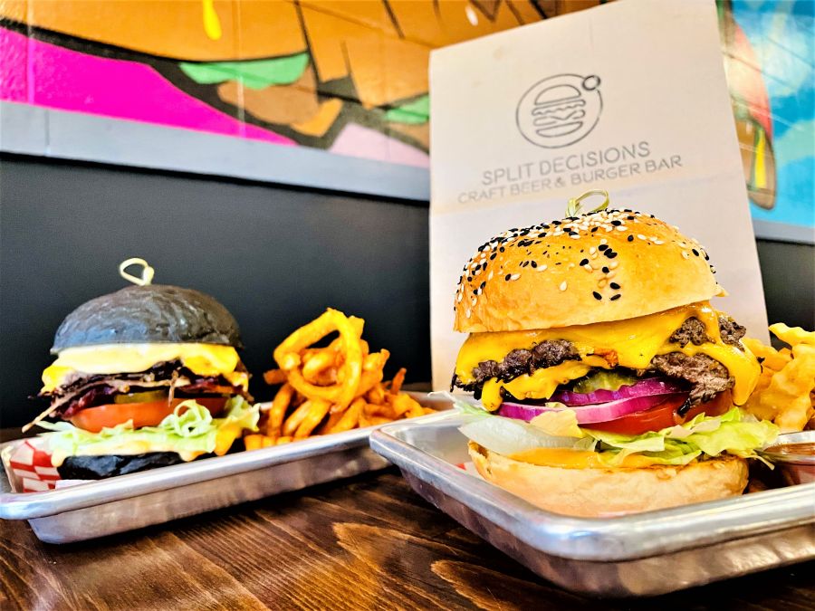 </who>Foreground is the Split D's signature smash-patty beef burger, background is the Carolina Reaper burger with Stoke the Fire hot sauce and black activated-charcoal bun.