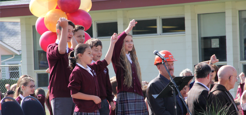 <who> Photo Credit: KelownaNow. </who> Students on stage, and off, celebrated the ground-breaking with a song. 