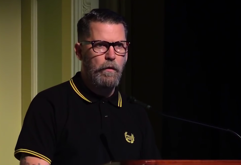 <who> Photo credit: YouTube </who> McInnes wearing a modified Fred Perry shirt.