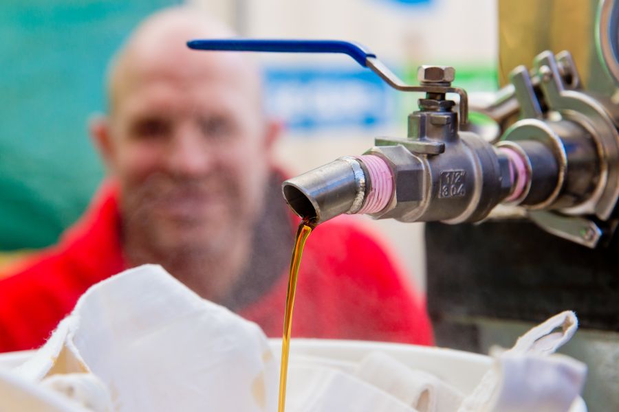 Denis Fontaine looks on as finished maple syrup pours from the faucet.