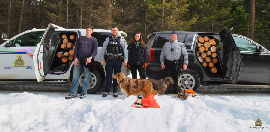 <who>Photo Credit: RCMP</who>Cst. Jonathan Stermscheg, Cst. Chris Hansen, PS Leanne McLaren and Cpl. Phil Peters stand in front of two police vehicles full of firewood.
